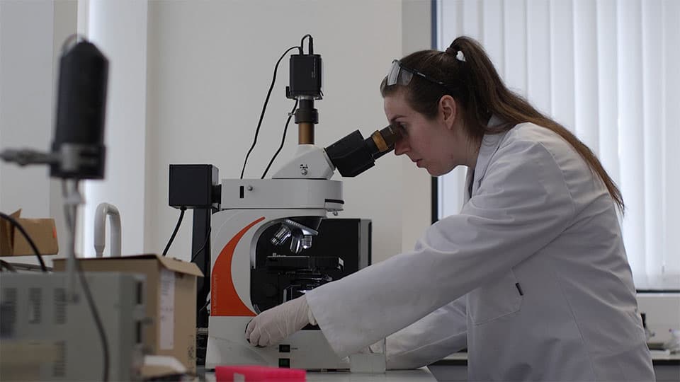 A woman looking into a microscope